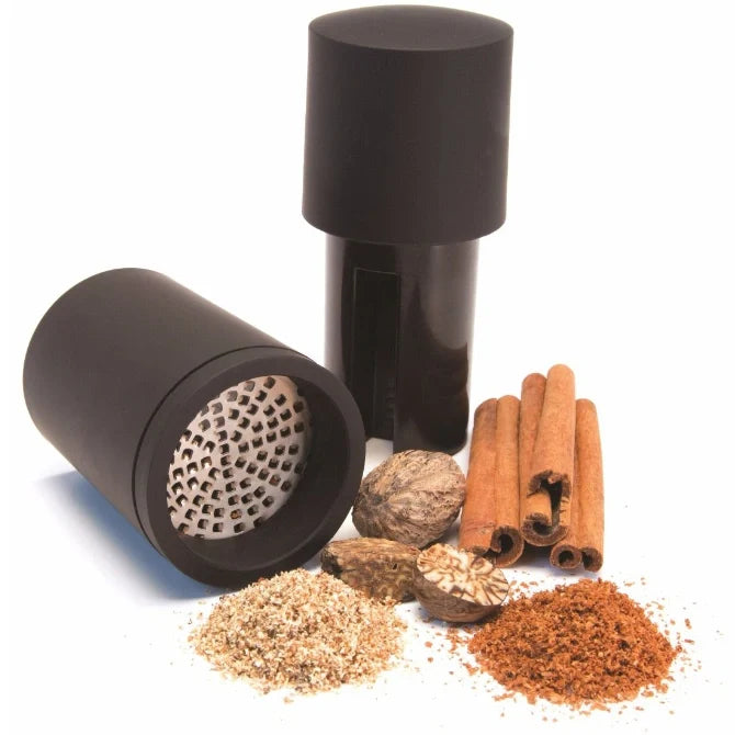 Black Microplane spice grinder with ground spices and whole spices on a white background