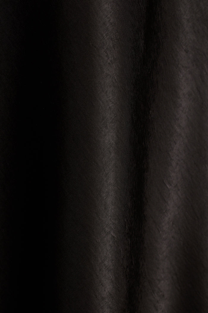 Close-up of black satin fabric with soft draped folds.
