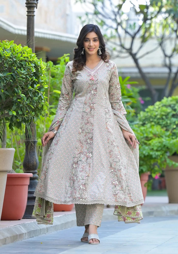 Woman in a floral dress standing outdoors with greenery in the background