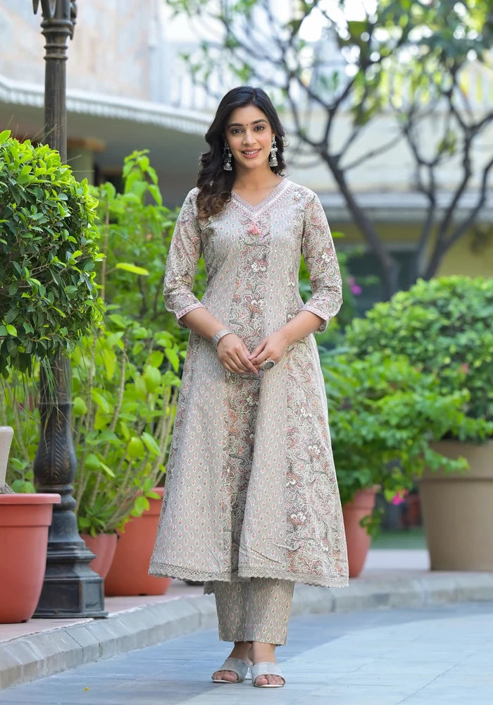 Woman in traditional outfit standing outdoors with greenery