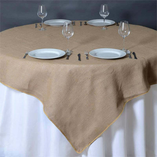Burlap tablecloth on a round table set for dining with plates and glasses.