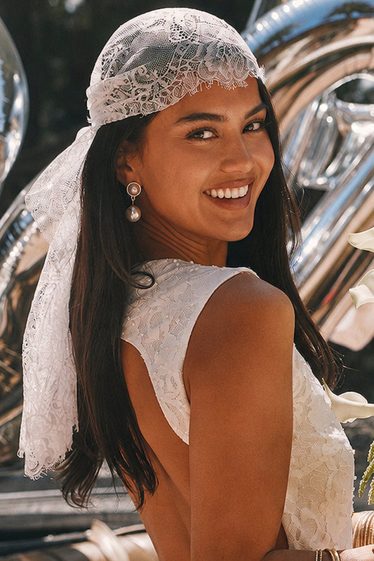 Lace kerchief headscarf tied at the nape, worn with a pearl drop earring and open-back lace top.