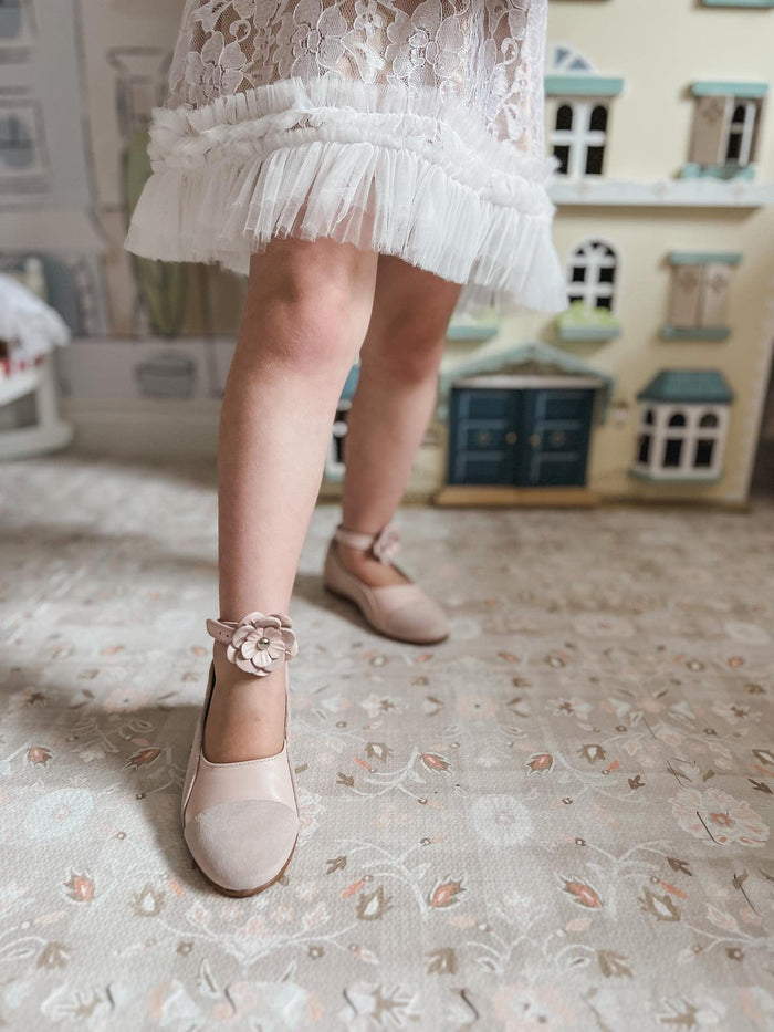 Toddler wearing Faina pink leather Mary Janes with flower strap detail and soft suede toe, classic girls dress shoes for special occasions