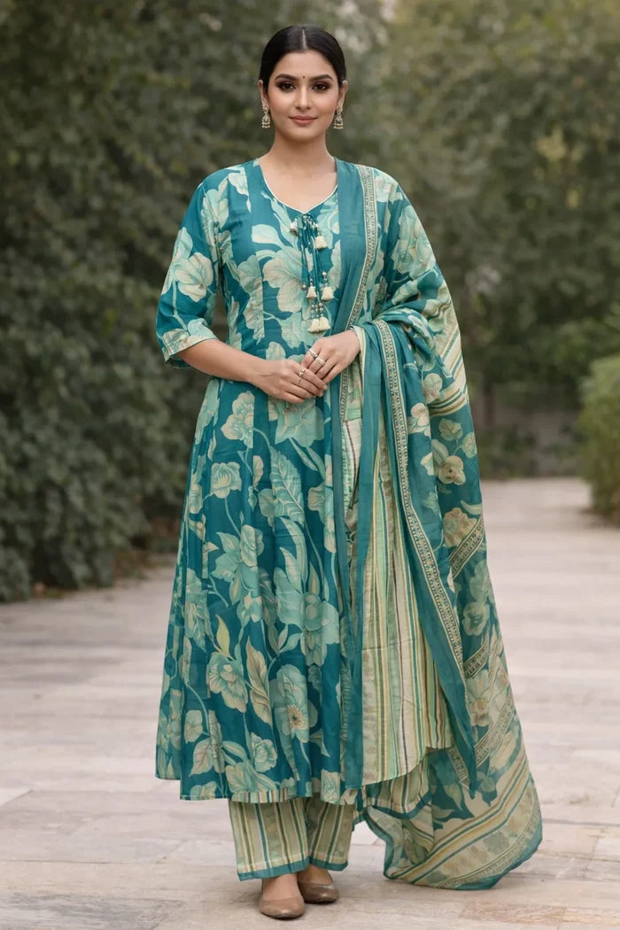 Woman wearing a teal floral traditional outfit with a matching dupatta outdoors.