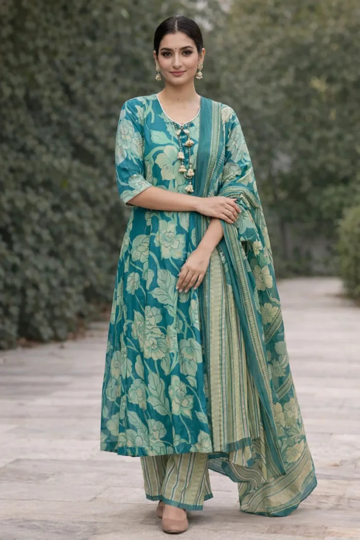 Woman wearing a teal floral outfit with a matching dupatta on a wooden path.