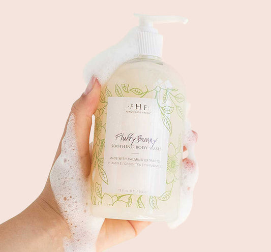 Hand holding a foaming bottle of Fluffy Bunny® Soothing Body Wash | Farmhouse Fresh with calming botanical design on the label, highlighting skincare and soothing body care.