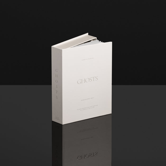 White book titled 'GHOSTS' on a reflective black surface with a black background