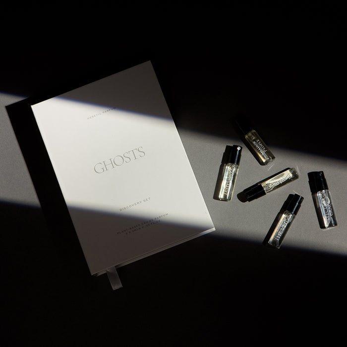 Set of small bottles and a book titled 'Ghosts' on a dark surface