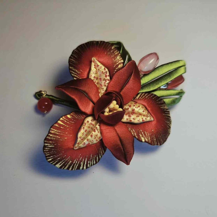 A traditional Chinese thread-wrapped (Chanhua) floral pin depicting a red iris and buds with intricate 3D artisanal textures.