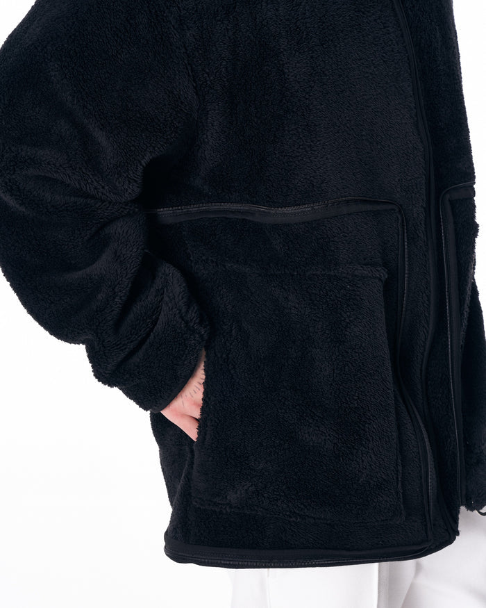 Martin Valen black plush cardigan close-up showing soft pile texture and horizontal zip pocket detail