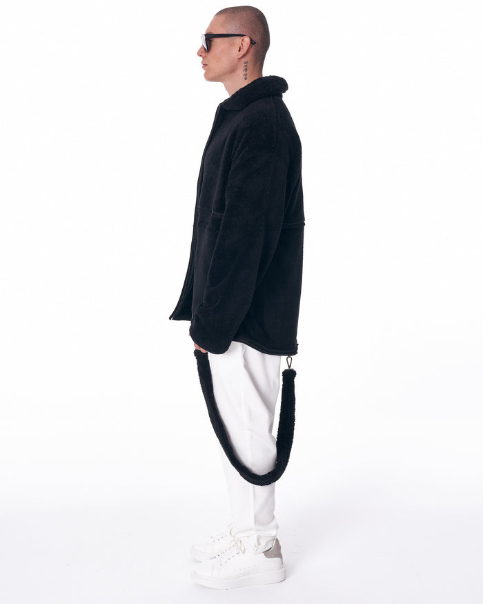 Martin Valen black plush cardigan, pocket-area shot with hand in pocket and visible zip hem detail