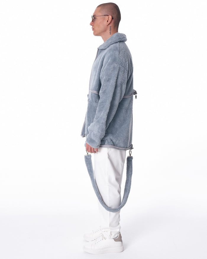 Martin Valen gray plush cardigan, side view of lower torso with hand in pocket and contrast hem and zipper trim visible