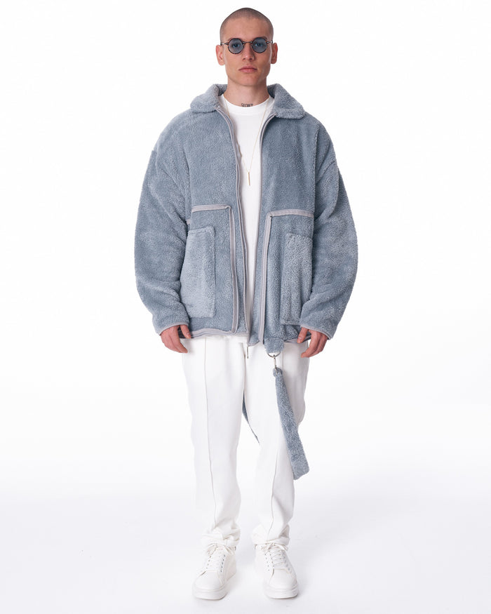 Martin Valen men's gray plush cardigan, full front view with open zip and plush strap falling alongside the white trousers
