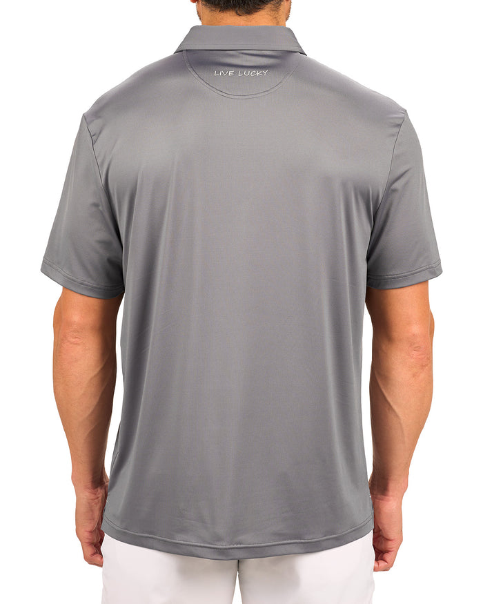 Man wearing charcoal grey polo from black clover featuring a small clover logo below the bottom button