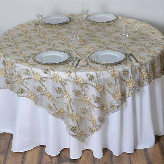 Round table covered with elegant gold floral lace tablecloth and white plates.