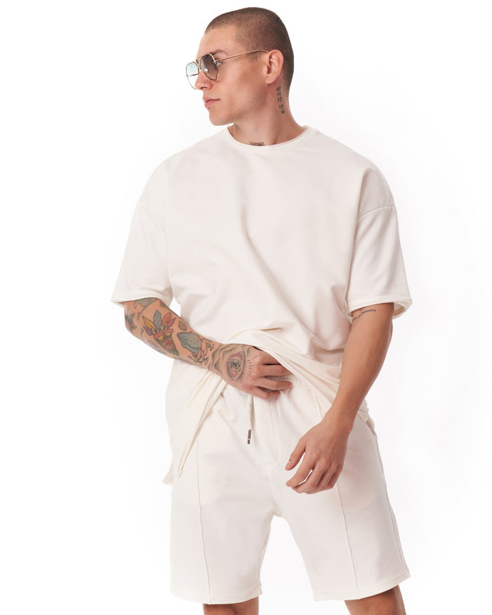 Martin Valen men's oversized white shortsuit, close-up upper body view with model wearing sunglasses and crew neck