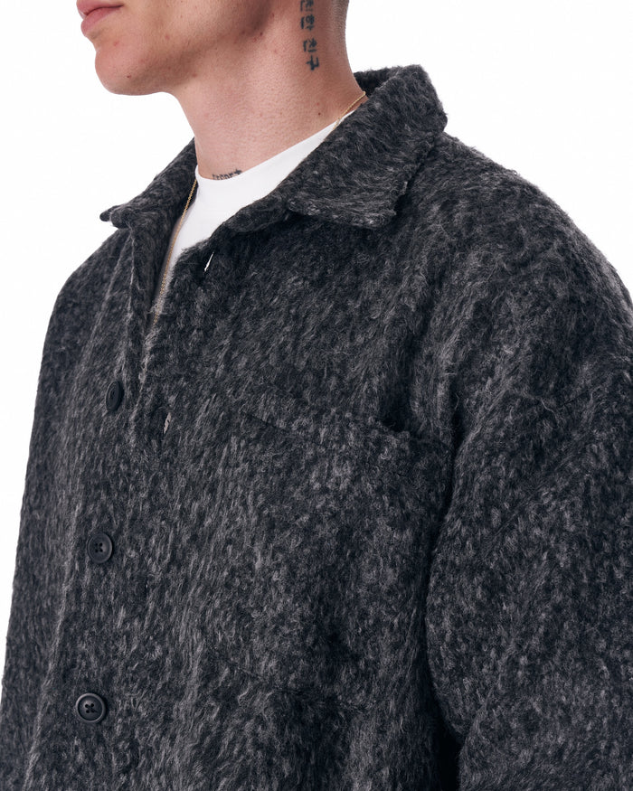 Martin Valen dark grey button-down wool cardigan, side view showing long sleeves and hem over white trousers