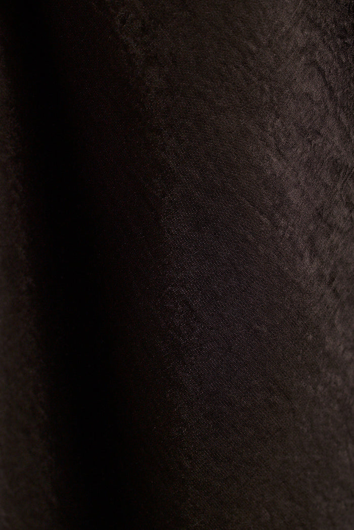 Close-up of black satin fabric with soft draped folds.