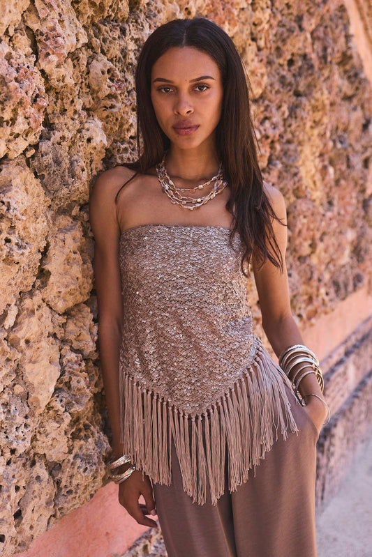 Taupe sequin strapless fringe top worn with matching wide-leg pants against a coral stone wall.