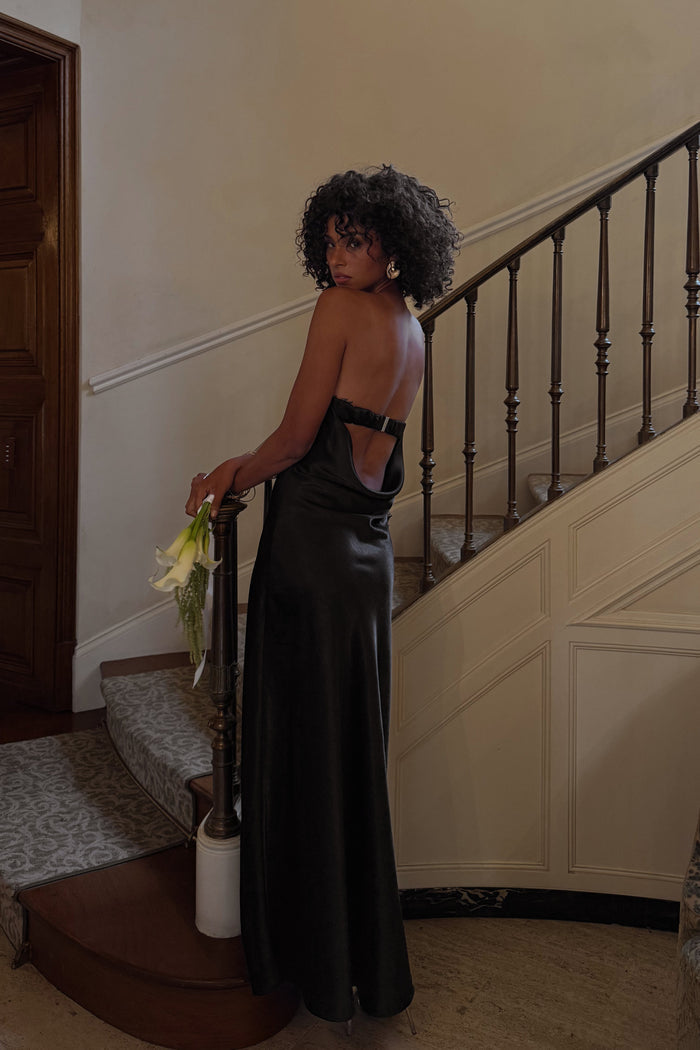 Back view of a black strapless satin maxi dress with an open cowl back detail.