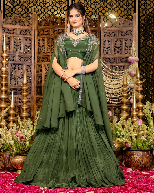 Woman in an olive green pleated lehenga with an embroidered blouse and matching sheer cape.