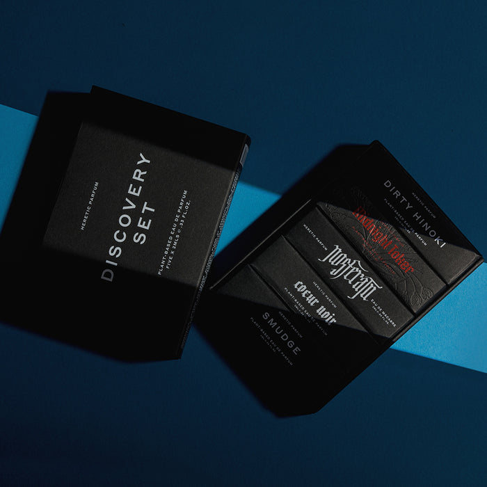 Two black cigarette packs arranged on a blue background. One pack is labeled 'DISCOVERY SET' and the other shows individual packs including 'DIRTY HINOI', 'PASTYCYMP', 'COCONUT WIP', and 'SMUDGE'.