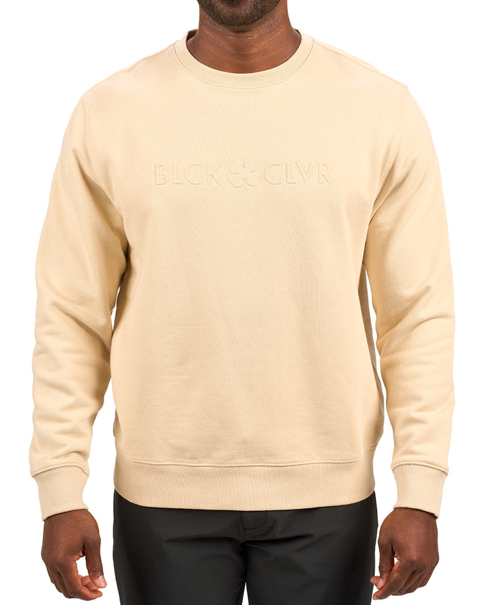 man wearing an oatmeal colored sweater from Black Clover with a 3d text BLCK CLVR on the chest