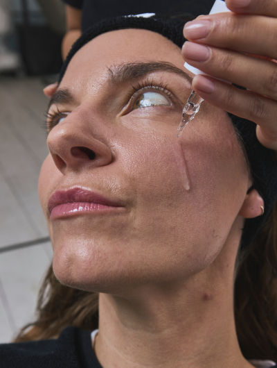 a woman dripping a drop of liquid into her eye
