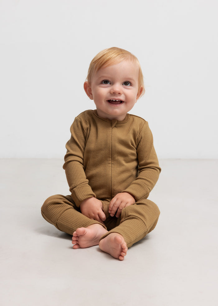 Baby wearing a ribbed brown jumpsuit in soft material with long sleeves and long legs and a zipper