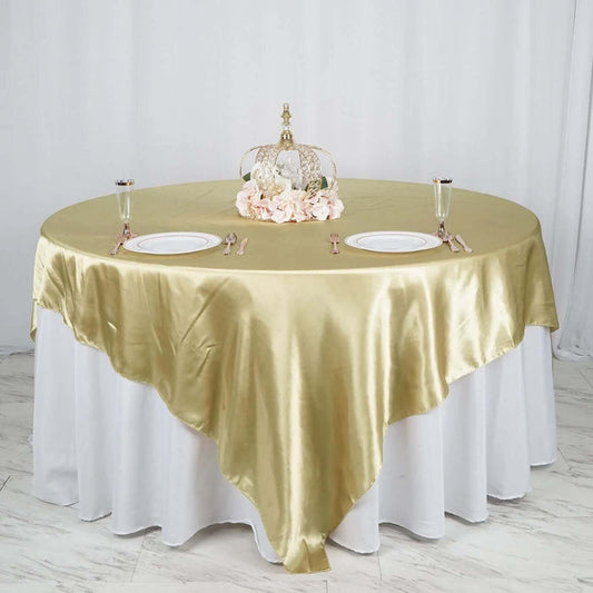 Elegant gold satin tablecloth draped over a round table with floral centerpiece.