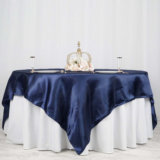 Elegant navy satin tablecloth draped over a white table with floral centerpiece.