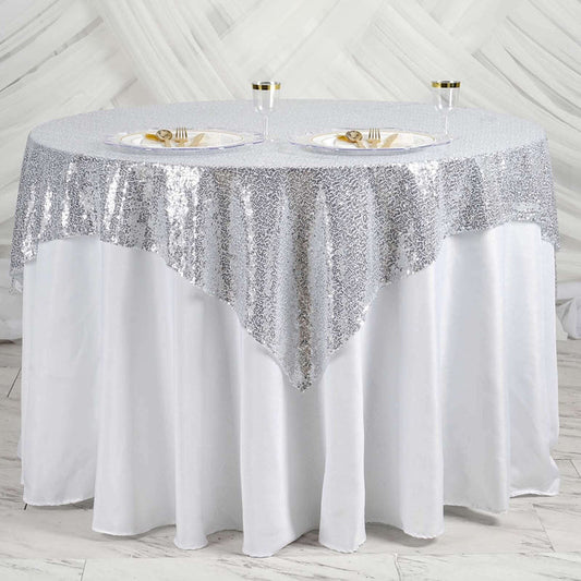 Round table with silver sequin tablecloth and elegant place settings.