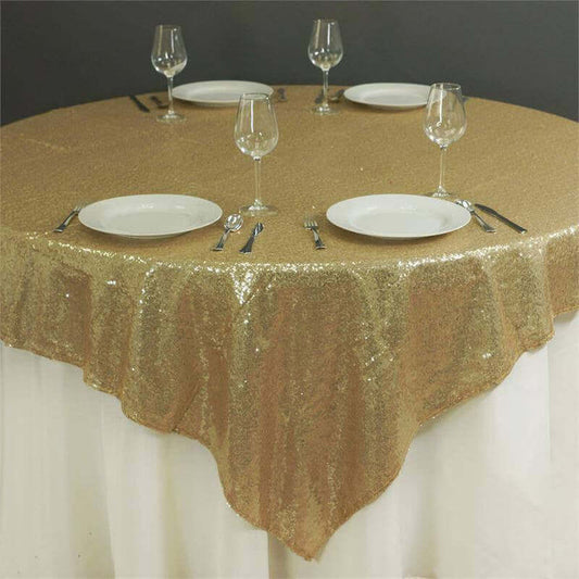 Gold sequin tablecloth on a round table set with plates and glassware.