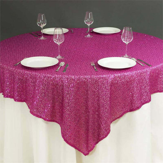 Pink sequin tablecloth on a round table set for dining.