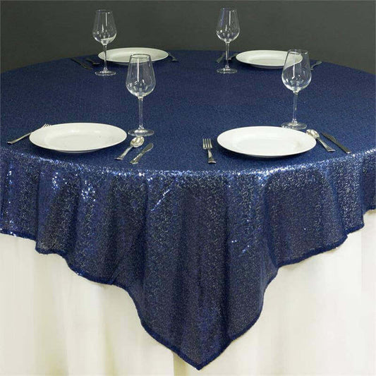 Navy blue sequin tablecloth with plates and glasses set for dining.