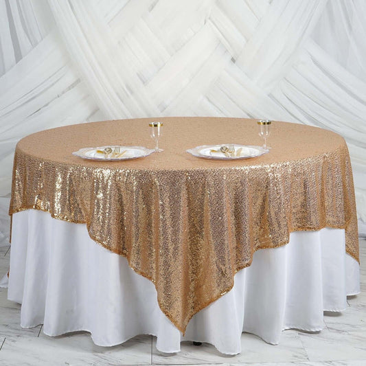 Gold sequin tablecloth draped over a round table with plates and glasses.