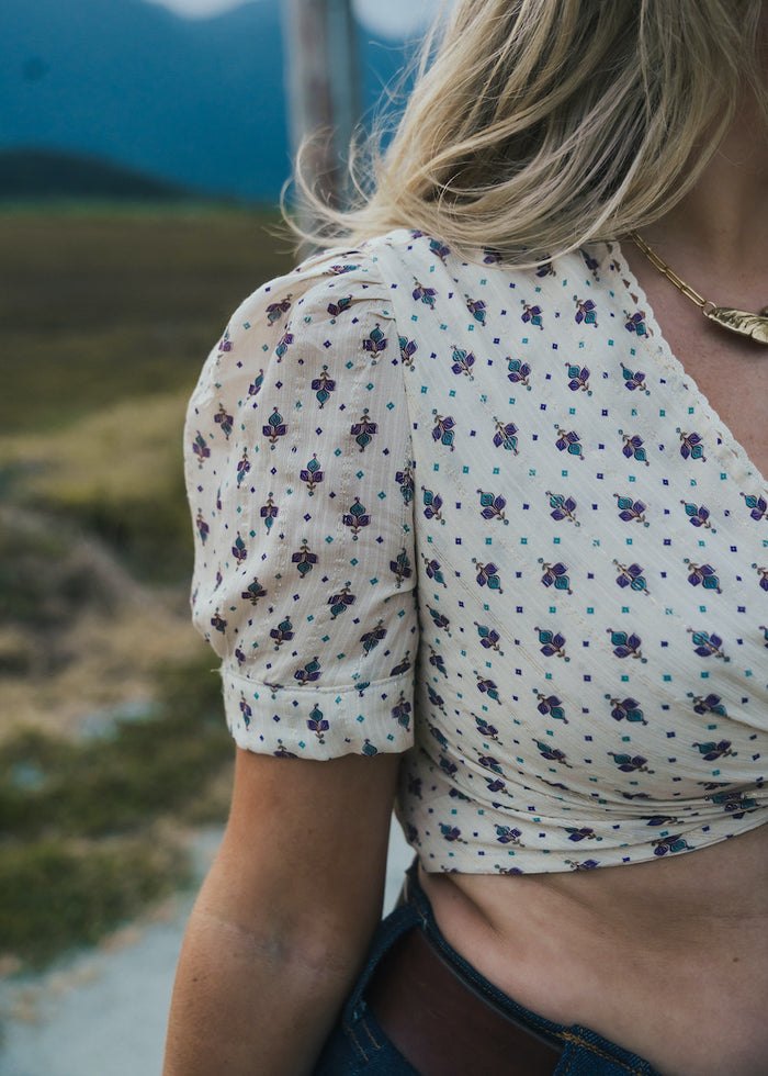 Person wearing a floral blouse with a blurred natural background wearing Soul Sister since 1969.