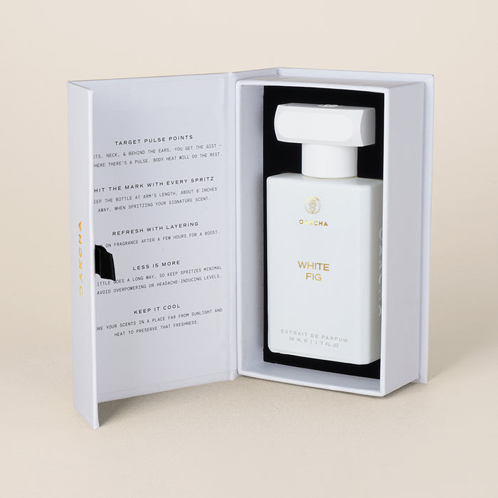 Three-quarter view of White Fig perfume bottle in open presentation box showcasing matte white rectangular bottle with gold logo on beige background