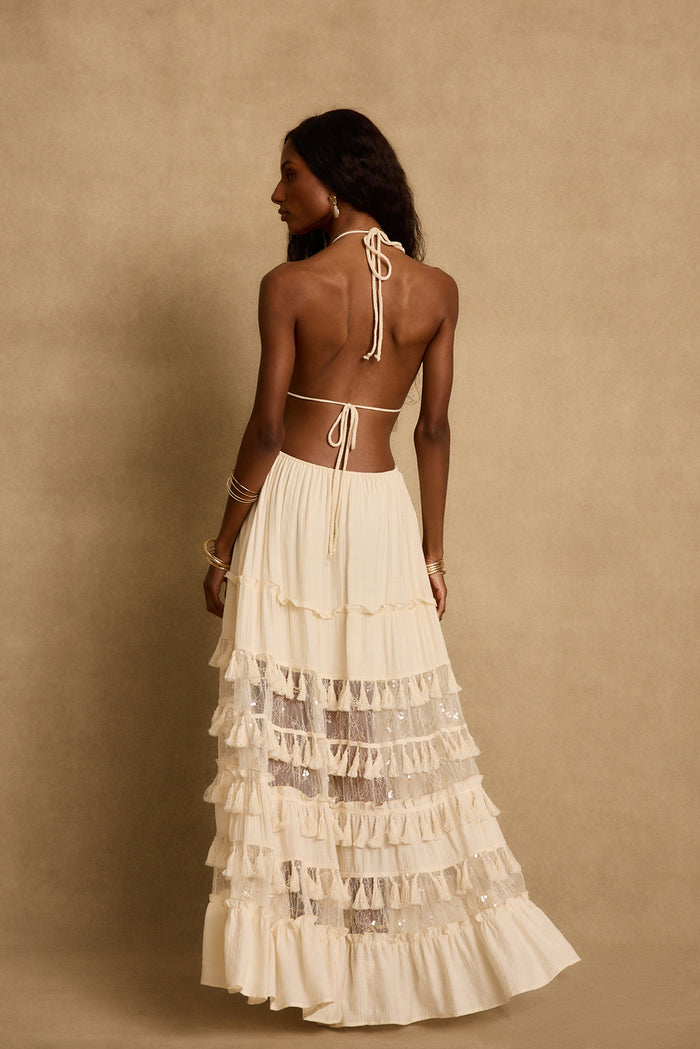 Open-back cream maxi dress with halter ties, tassel fringe tiers and sheer lace panels.