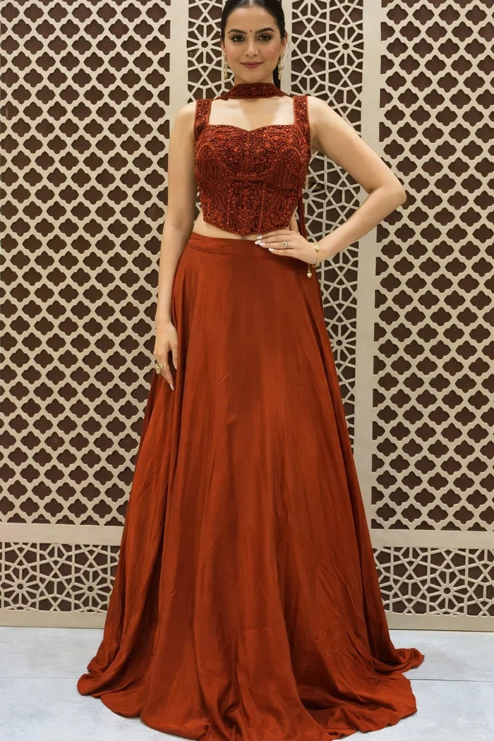Woman wearing a rust-colored outfit with a patterned wall background