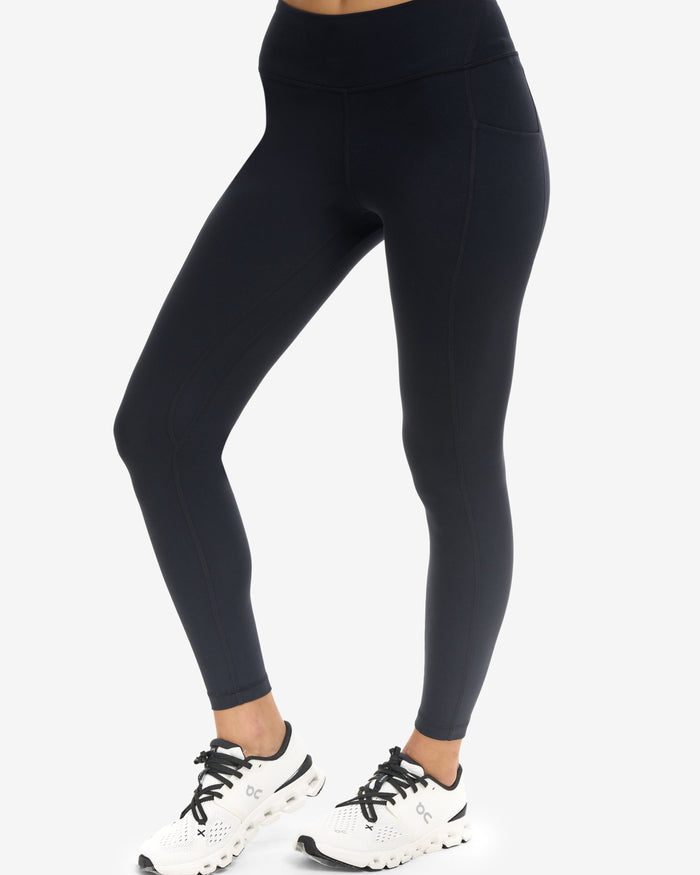 Person wearing black leggings and white sneakers on a white background