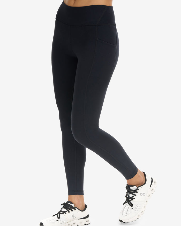 Person wearing black leggings and white sneakers on a white background