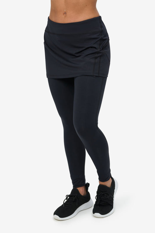 Person wearing black leggings with a matching skirt on a white background